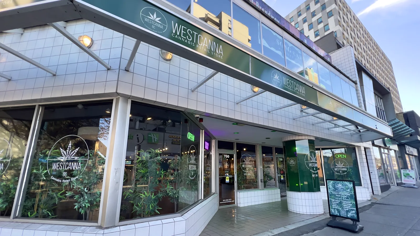 The WestCanna BC store at 700 West Broadway: white tile, the green WESTCANNA fascia over the corner windows, the green pillar and the door at number 700.