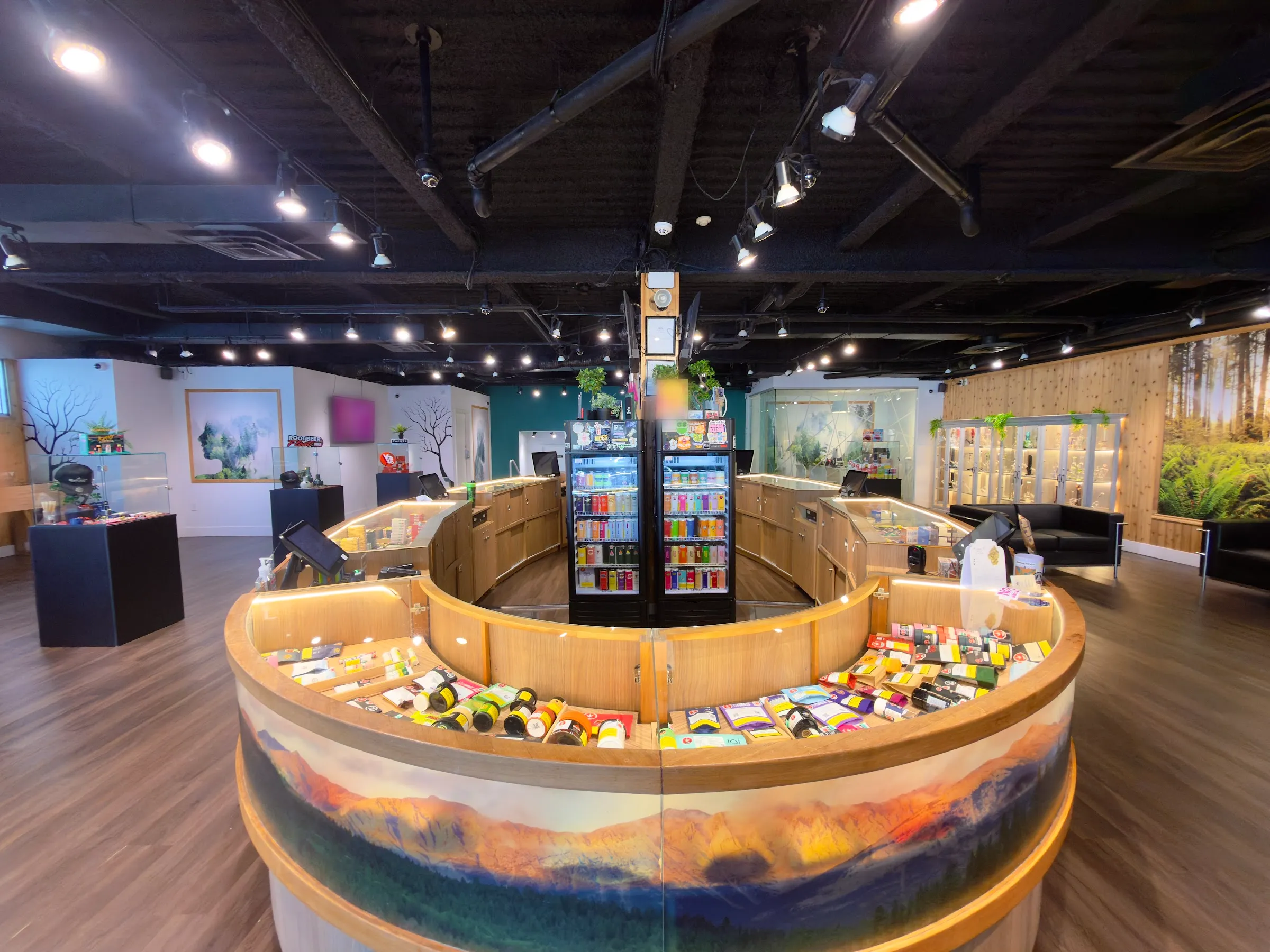 Inside WestCanna Broadway: the round cedar counter with its painted mountain mural, the drinks coolers and the forest wall
