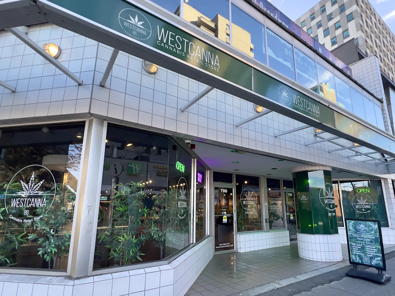 The WestCanna BC store at 700 West Broadway: white tile, the green WESTCANNA fascia over the corner windows, the green pillar and the door at number 700.