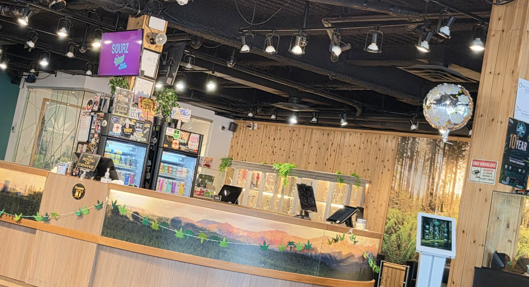 Inside 700 West Broadway: the round cedar counter with its painted mountain mural, cedar posts and a forest wall.