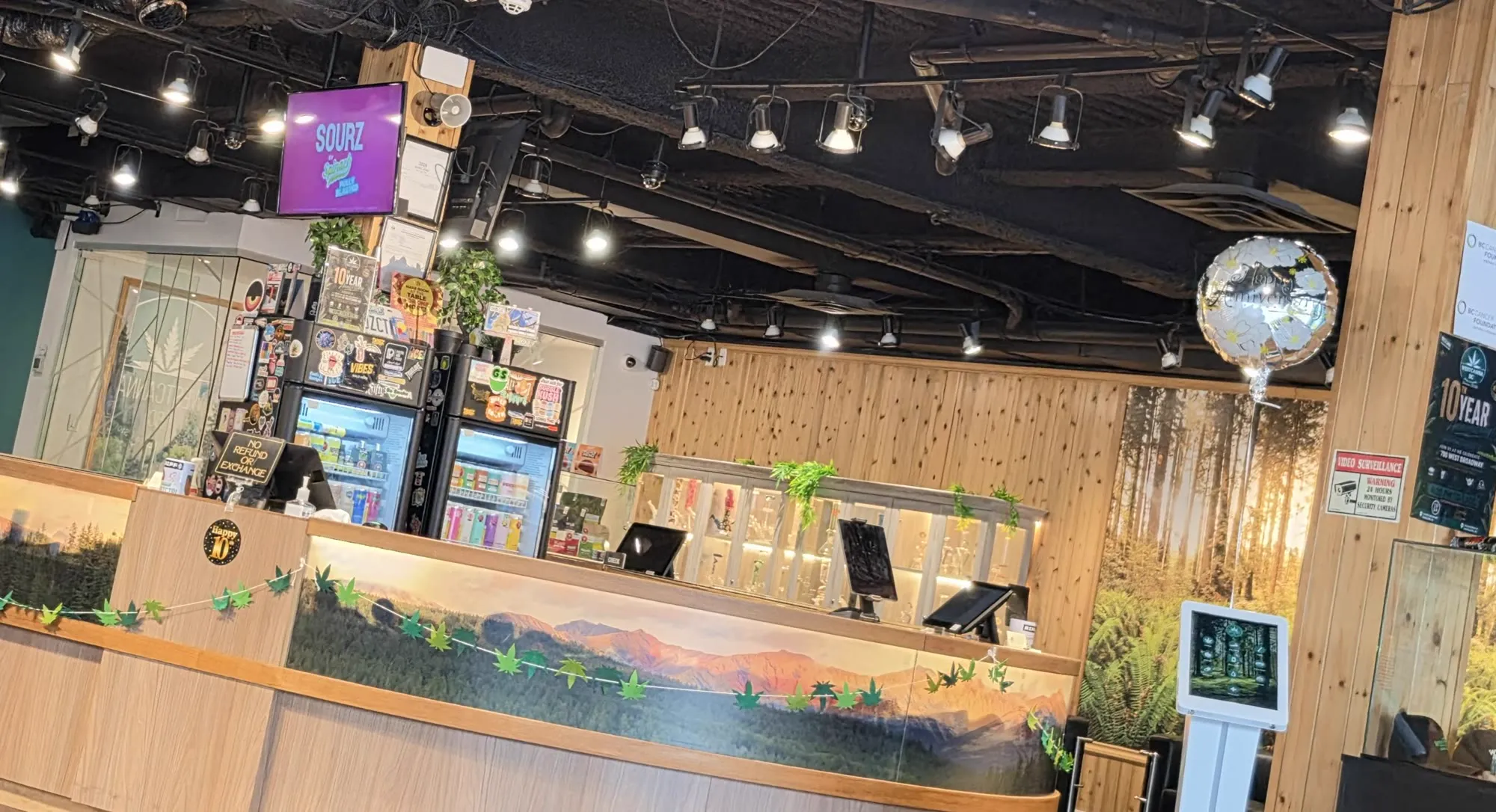 Inside 700 West Broadway: the round cedar counter with its painted mountain mural, cedar posts and a forest wall.