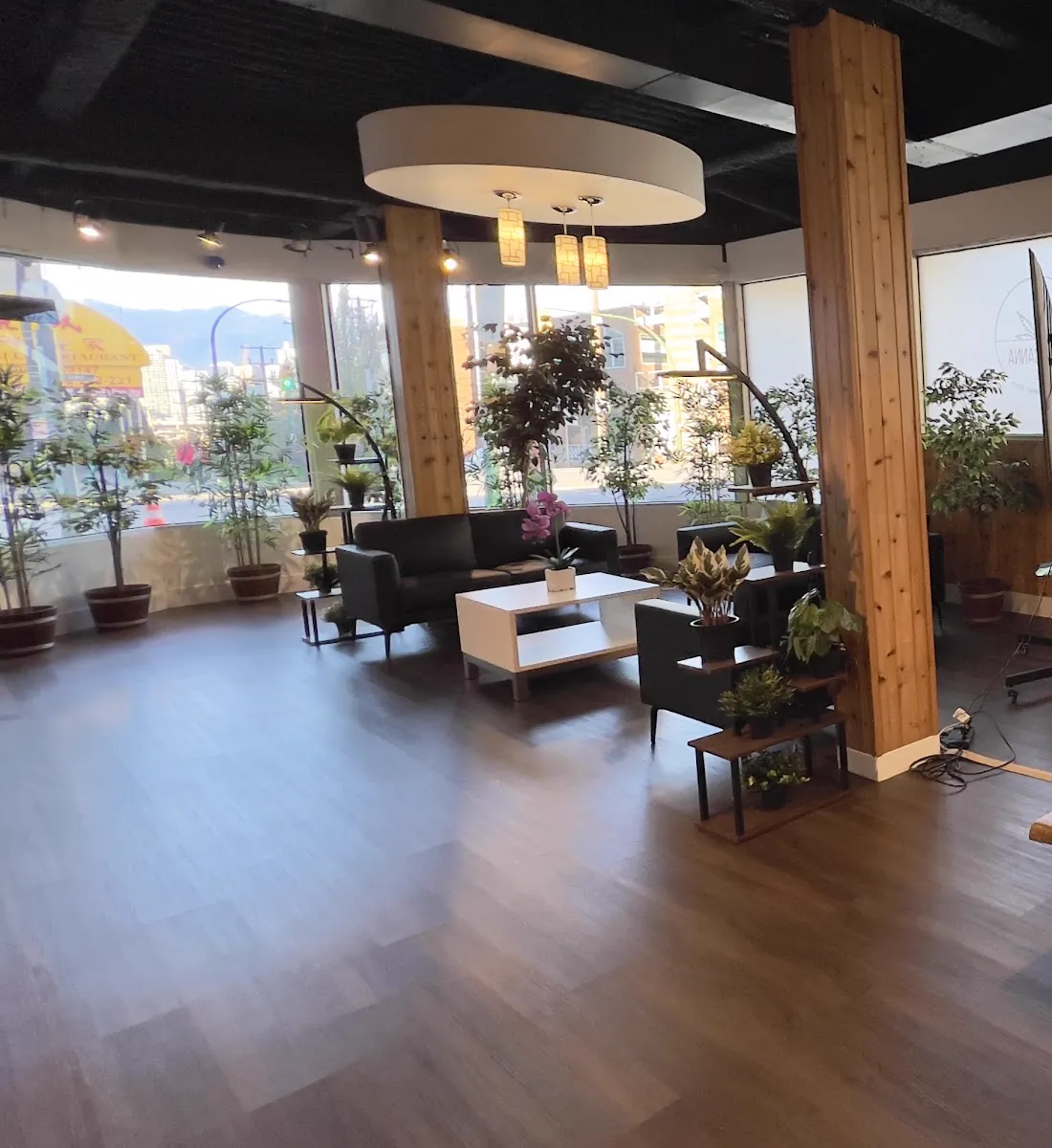 Inside WestCanna Broadway: the seating area by the front windows, with a cedar pillar and plants.