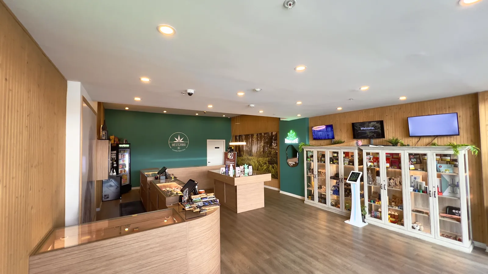 Inside WestCanna Robson: the wood counters, the display table, the WESTCANNA BC emblem on the green wall and the accessory cabinets.